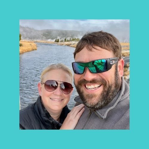 Selfie of Bear & Taibrie standing on a bridge with the Firehole River in Yellowstone National Park behind them.